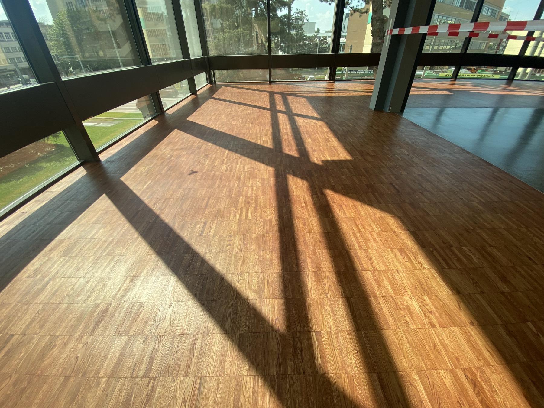 Frisch verlegtes Parkett mit Sonnenlicht und Fensterschatten